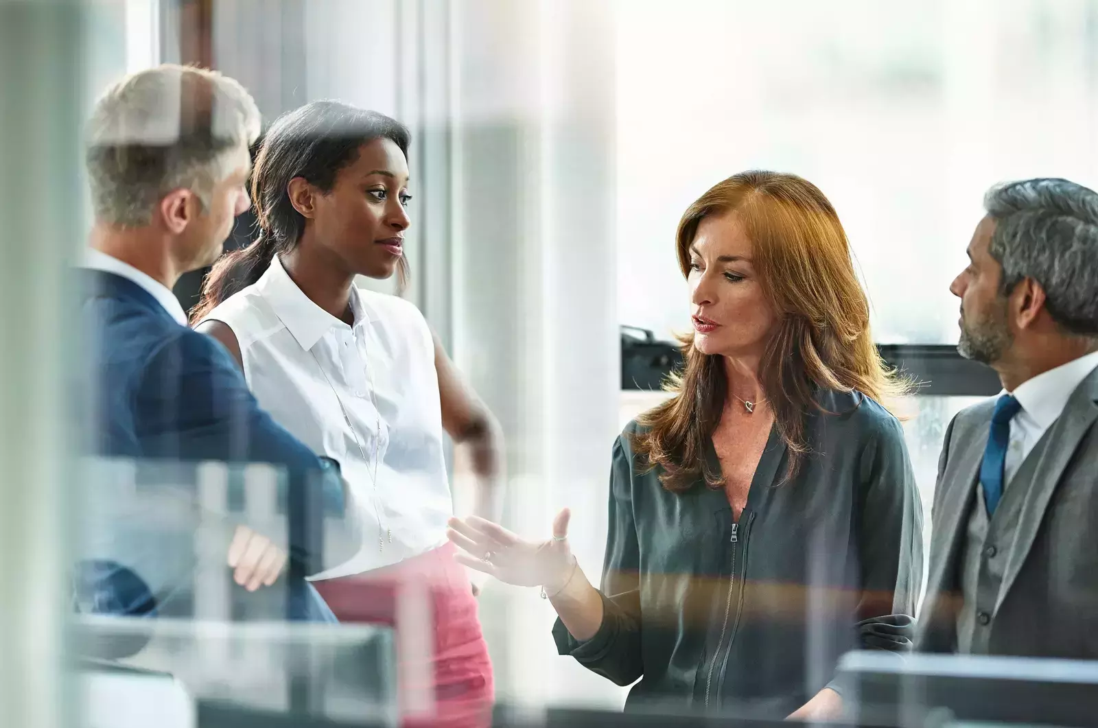 HR executives behind glass standing in conference room discussing pay equity