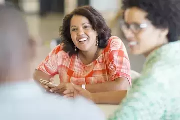 HR professional leaning in on conference table and smiling while discussing employer brand ideas