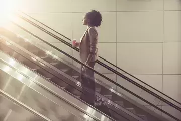 Woman moving up escalator retraining and reskilling concept