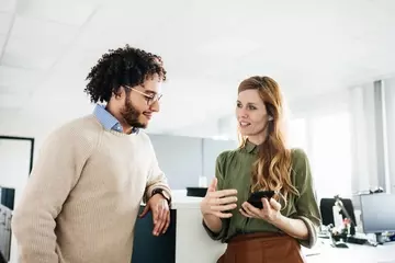 Employee showing colleague work on phone