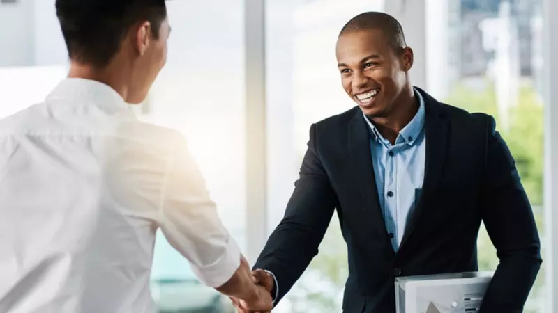 A hiring manager shakes hands with an interview candidate 